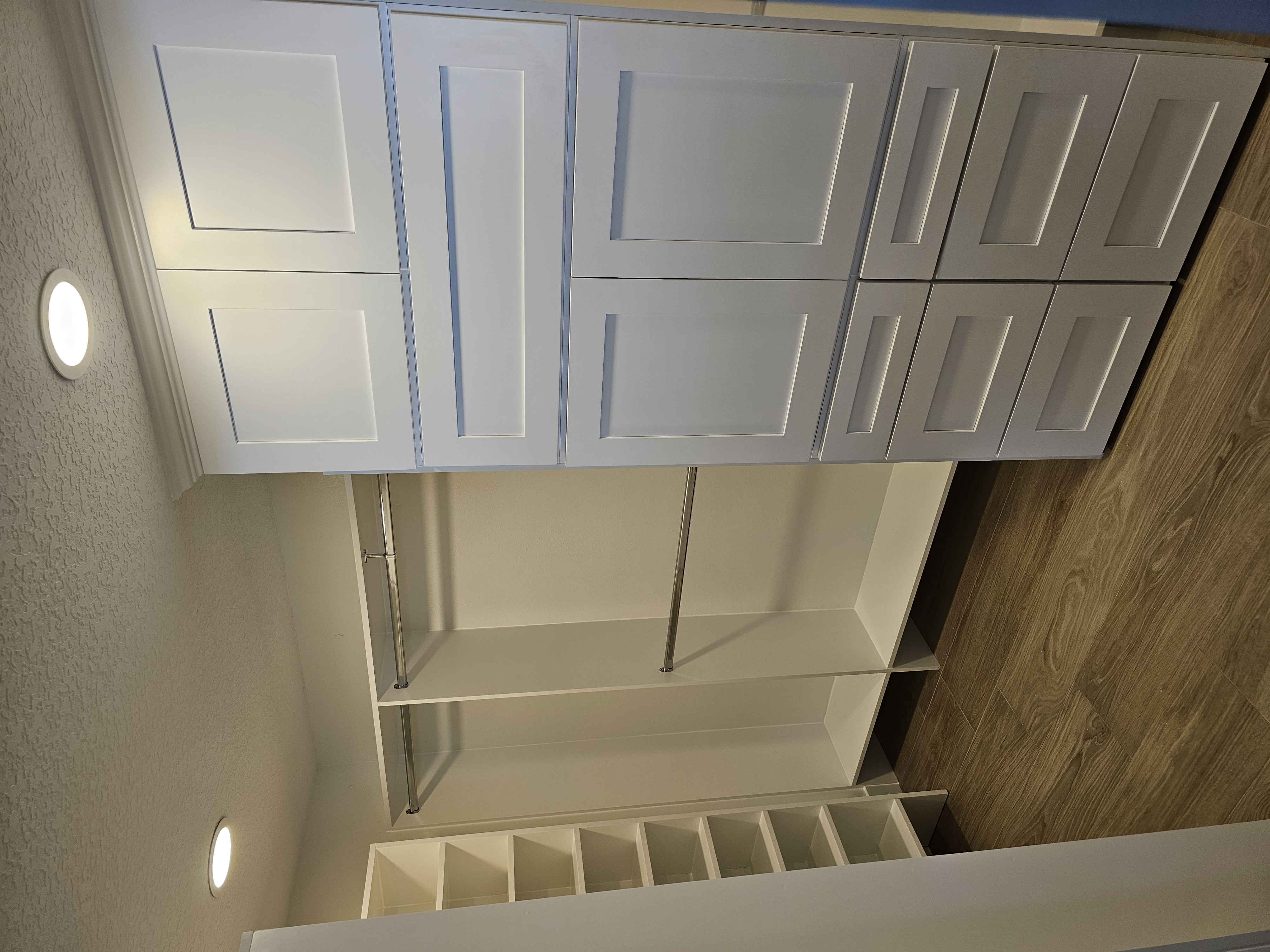 Walk-in closet with white Shaker-style cabinets, a drawer bank, open shoe shelving, and double hanging rods