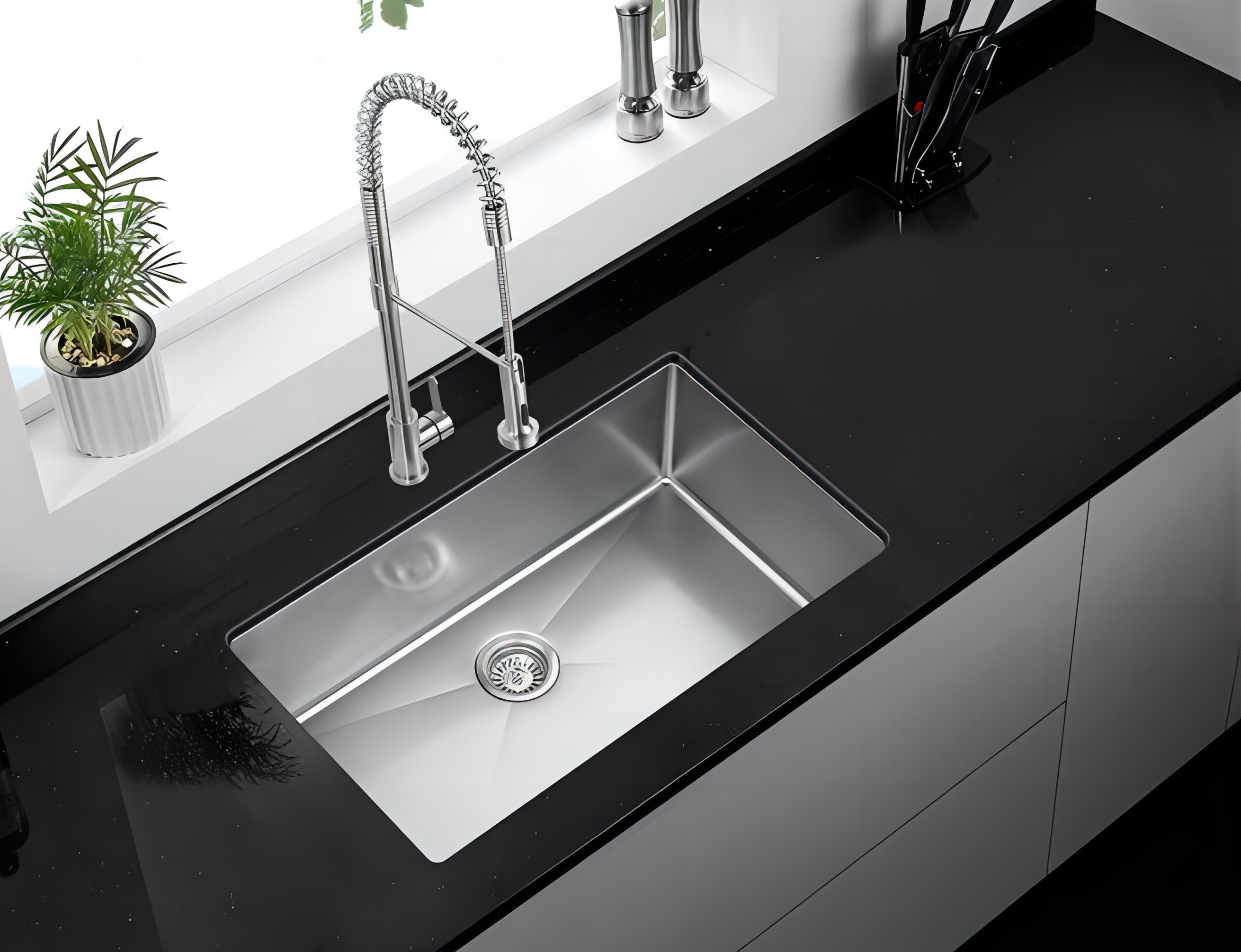 Stainless steel single bowl undermount sink with a pull-down faucet in a black countertop